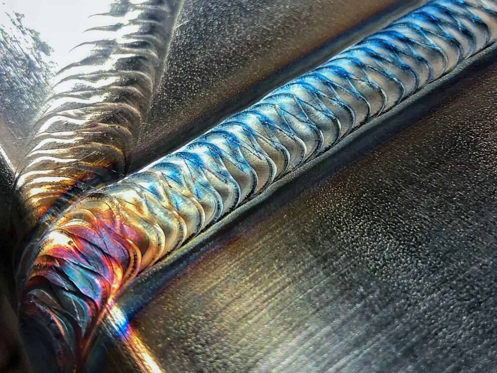 Close-up photograph showing stainless steel TIG welds with increasing levels of heat tint